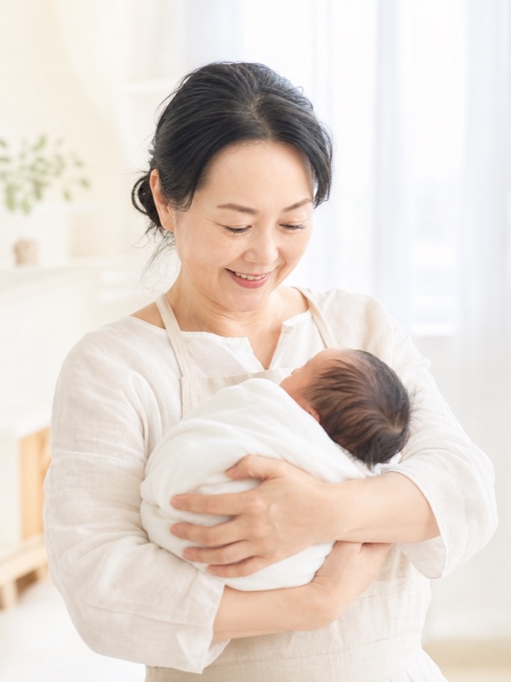 こもれび助産院 院長・助産師の佐倉みどり。赤ちゃんを抱いて微笑んでいる
